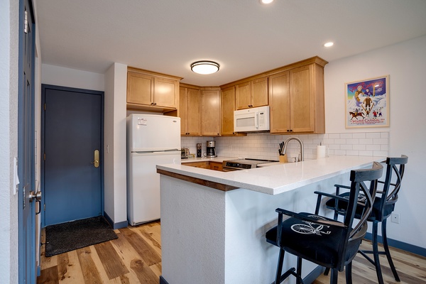 Step into your fully equipped kitchen with warm wood cabinetry, modern appliances, and a breakfast bar perfect for morning coffee or casual meals with loved ones.