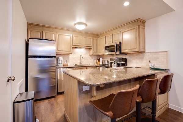 Your fully equipped kitchen with stainless steel appliances, granite countertops, and a breakfast bar awaits, perfect for preparing meals or enjoying morning coffee in style.