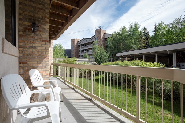 Private balcony overlooking green lawns and neighboring buildings, featuring comfortable seating where you can unwind and enjoy the peaceful surroundings in the fresh air.