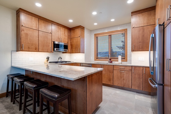 Your fully equipped kitchen features sleek granite countertops, stainless steel appliances, and a spacious island with seating—perfect for cooking and gathering together.