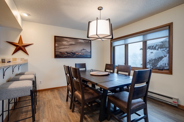 Gather around this inviting dining table where you'll share memorable meals with loved ones while enjoying natural light and serene winter views through the large windows.
