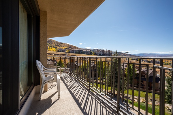 Balcony overlooking mountains and seasonal foliage, with nearby resort buildings in view. Outdoor seating included for enjoying the surrounding landscape.