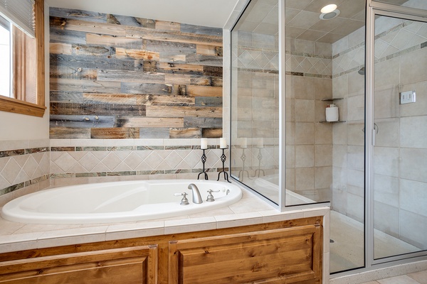 Unwind in your private spa-like bathroom with a soaking tub for relaxation and a walk-in shower framed by elegant tile and rustic wood accents.