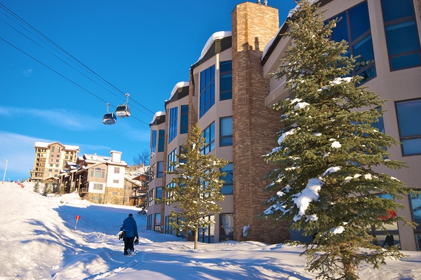 Ski-in, ski-out property nestled on the snowy slopes with mountain gondola access, offering direct access to winter adventures beneath brilliant blue skies.