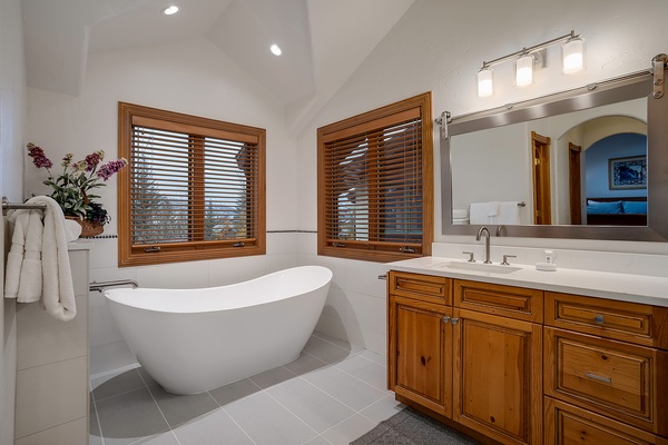 Sink into the freestanding tub after a long day, where natural light filters through wooden blinds and creates your own private spa retreat.