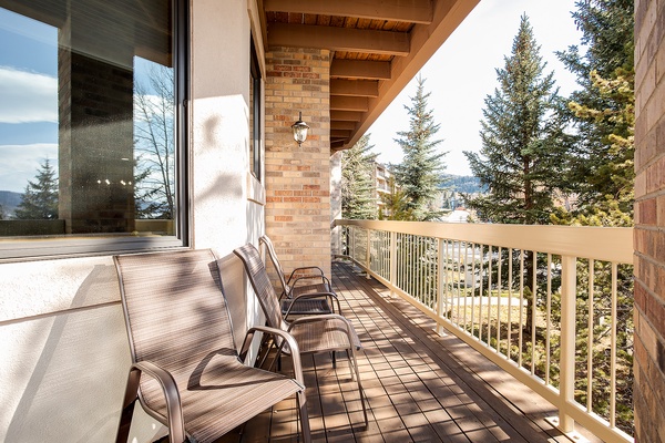 Step onto your private balcony and breathe in crisp mountain air as sunlight streams across comfortable lounge chairs overlooking towering pines and distant peaks.