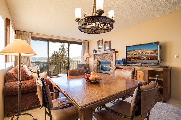 Settle into your cozy retreat with stunning mountain views through expansive balcony doors. Gather around the dining table, warm up by the fireplace, and enjoy home entertainment in this inviting space.