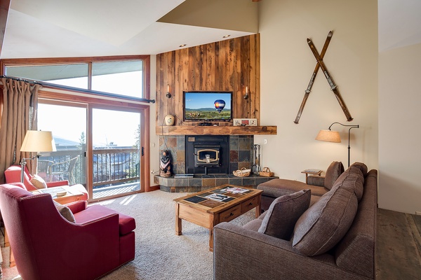Picture yourself unwinding in this bright, spacious living room with soaring ceilings, cozy fireplace, and stunning mountain views through floor-to-ceiling windows—your perfect retreat after a day of adventure.