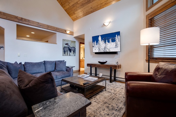 Sink into plush seating in your mountain-modern living room, where vaulted wood ceilings and thoughtful design create the perfect retreat after an adventure-filled day.