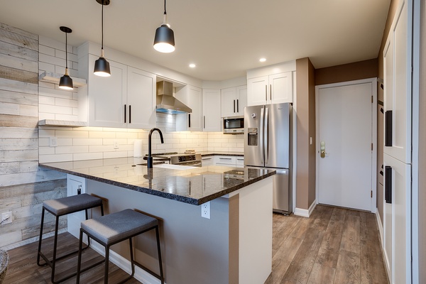 Your modern kitchen awaits with gleaming granite counters, stainless steel appliances, and a breakfast bar perfect for morning coffee or casual meals.