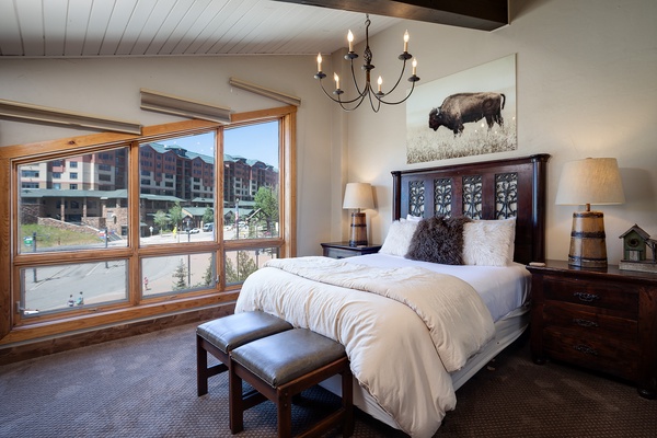 Sink into plush bedding beneath a rustic chandelier, with textured pillows and mountain-inspired décor inviting you to unwind in style.