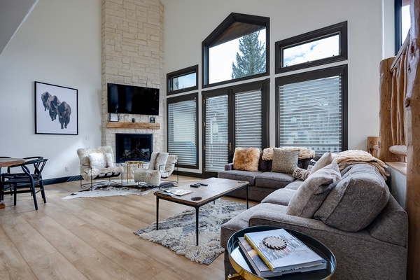 Unwind in your spacious living room with soaring ceilings, a warm stone fireplace, and plush seating designed for ultimate comfort. Natural light floods through oversized windows.