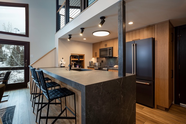 Your gourmet kitchen invites you to create culinary masterpieces at this sleek island, while natural light pours in through expansive windows framing serene winter views.