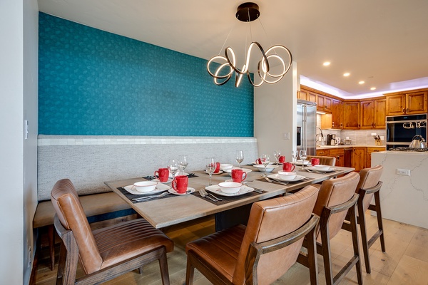 Gather around your private dining table, where a striking teal accent wall and modern chandelier create the perfect setting for memorable meals with loved ones.