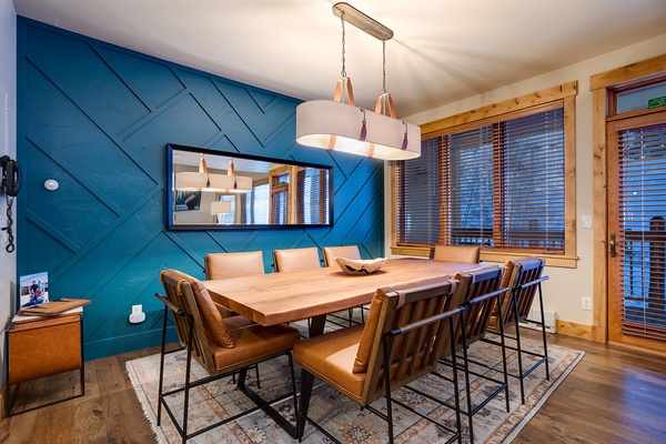 Gather around this stunning live-edge table beneath modern pendant lighting. The bold blue accent wall and warm leather chairs create an inviting space for meals and conversations you'll cherish.
