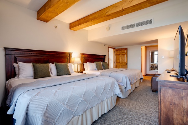 Sink into crisp linens and unwind beneath rustic beams. Two plush beds invite restful nights, while natural wood details and modern comfort create your perfect mountain retreat.