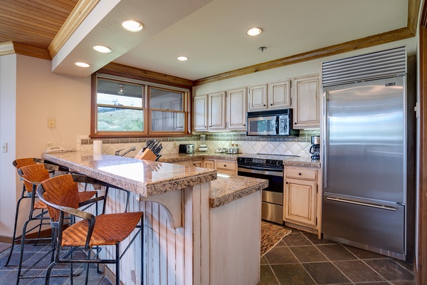 Your fully equipped kitchen features granite countertops, stainless steel appliances, and an inviting breakfast bar perfect for casual meals and morning coffee.