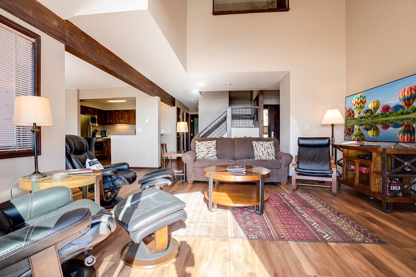 Unwind in your spacious living room where exposed beams meet modern comfort. Sink into plush seating, enjoy mountain views on the smart TV, and savor the warm hardwood floors beneath your feet.