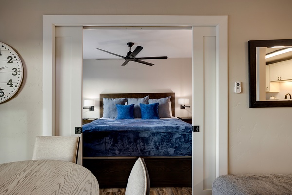 Step into your serene bedroom retreat with a plush bed dressed in rich blue linens, gentle bedside lighting, and a quiet ceiling fan to keep you comfortable all night.