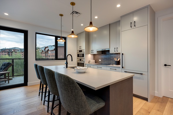 Your modern kitchen features sleek cabinetry, a spacious island with seating, and warm pendant lighting that creates an inviting space for cooking and gathering.