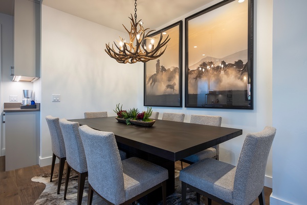 Gather around this striking dining table beneath a rustic antler chandelier, where your group can enjoy home-cooked meals together in a bright, modern space that blends warmth with style.