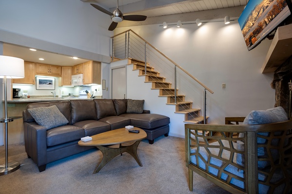 Relax in your bright, open living space with a modern sectional sofa, stylish coffee table, and fully equipped kitchen just steps away—perfect for unwinding after a day of adventure.
