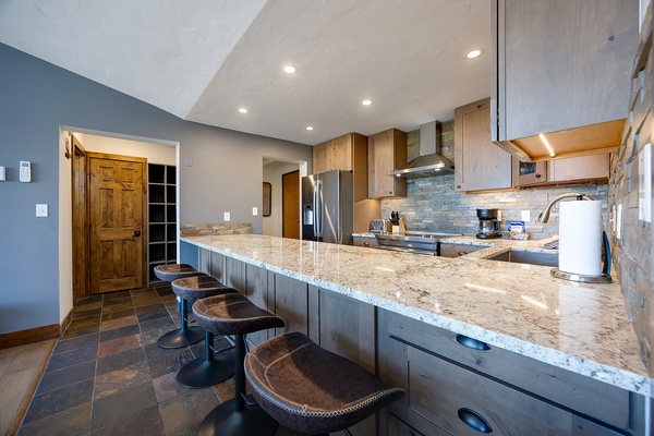 Gather around the expansive granite island with bar seating where you can prep meals, share stories, and enjoy modern appliances in this warm, welcoming kitchen space.