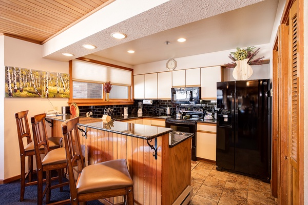 Your fully equipped kitchen invites home-cooked meals, featuring sleek granite countertops, modern black appliances, and a cozy breakfast bar perfect for morning coffee or evening conversations.