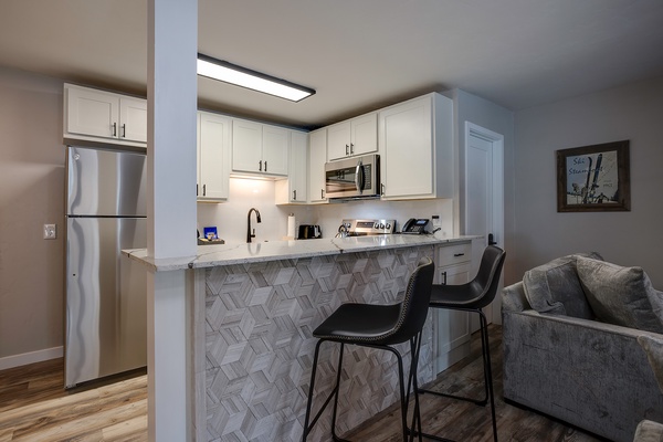 This stylish open-concept space features a fully equipped kitchen with modern appliances and a chic breakfast bar where you can enjoy your morning coffee.