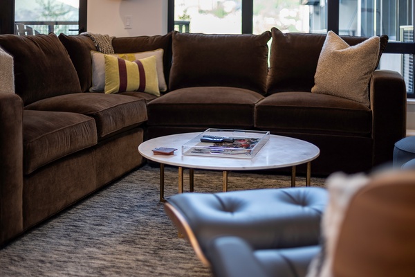Sink into plush velvet sofas and unwind in your bright living room, where a marble coffee table holds your favorite reads and windows frame soft natural light for cozy afternoons.