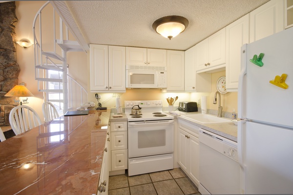 Your fully equipped kitchen invites you to prepare meals together, with bright white cabinetry, modern appliances, and a cozy breakfast table—perfect for morning coffee or family dinners.