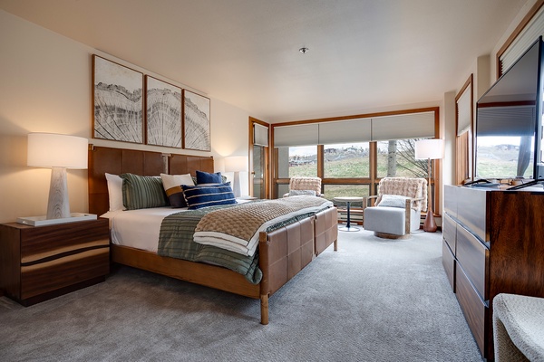 Sink into plush bedding and wake to stunning mountain views through expansive windows. Your peaceful retreat features warm wood tones, elegant artwork, and a cozy seating nook perfect for morning coffee.