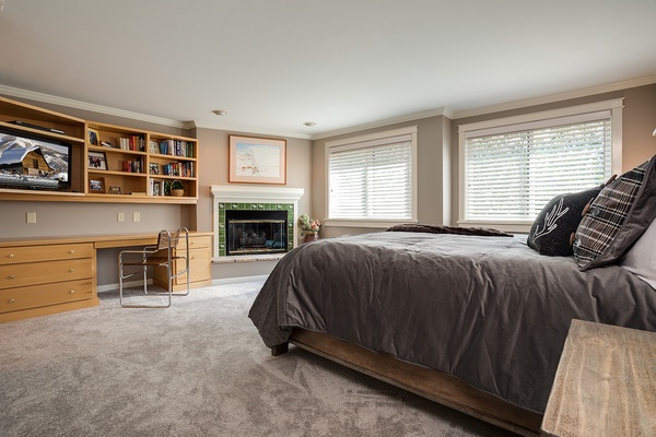 Picture yourself unwinding in this spacious bedroom with plush bedding, a cozy fireplace, and a dedicated workspace—your perfect retreat after mountain adventures.