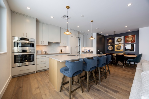 Modern open-concept kitchen and dining space featuring sleek appliances, bright white cabinetry, and stylish pendant lighting. Perfect for gathering at the spacious island or hosting memorable dinners.