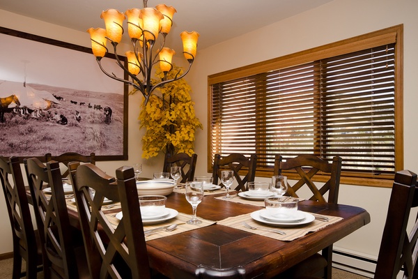 Gather around this handsome dining table with seating for eight, where memorable meals and laughter await beneath warm chandelier lighting and rustic touches.