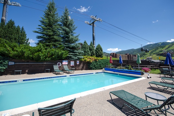 Sparkling pool nestled among evergreens with mountain vistas—your summer basecamp for alpine adventures. Lounge poolside under vibrant umbrellas and soak in the fresh air and views.