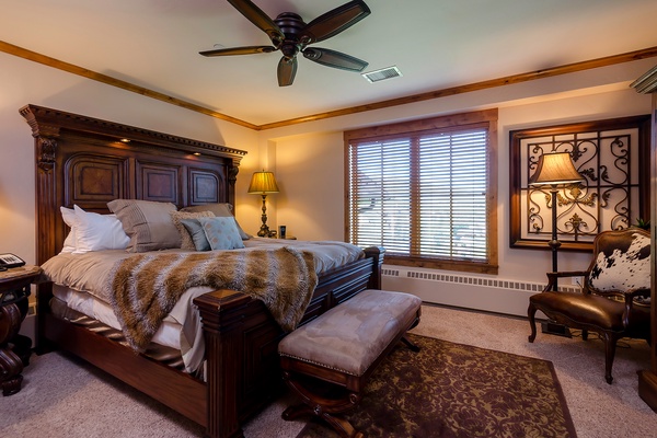 Sink into this luxurious bed with plush linens and a cozy fur throw, where your restful nights are cooled by a ceiling fan and warmed by elegant décor.