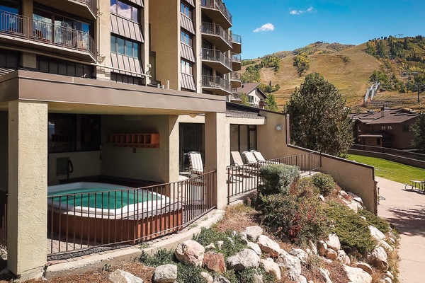 Multi-level property nestled in a mountain setting with poolside relaxation area, landscaped grounds, and scenic hillside views.