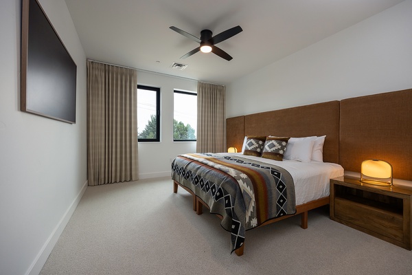 Your modern bedroom awaits with a plush bed, warm lighting, and a ceiling fan to keep you comfortable. Natural light spills through the windows, creating a serene space to unwind after your day.