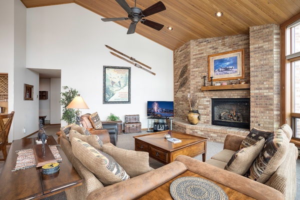 Relax in your inviting living room with soaring ceilings, warm wood tones, and a cozy fireplace—perfect for unwinding after your mountain adventures.