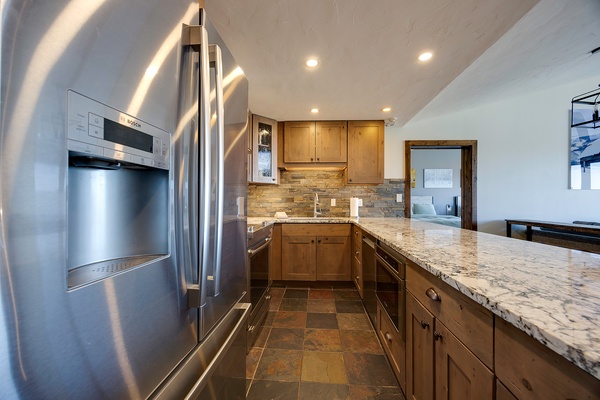 A modern kitchen awaits with gleaming granite countertops, warm wood cabinetry, stainless-steel appliances, and a rustic stone backsplash that adds character to your cooking space.