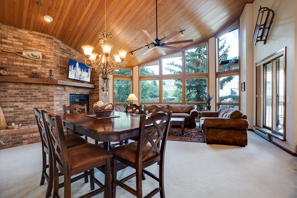 Gather around the warm brick fireplace or settle into plush leather seating while soaking in sweeping tree views through floor-to-ceiling windows. A perfect spot for meals, conversations, and unwinding together.