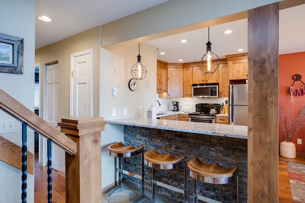 Your vacation kitchen features modern appliances, stylish pendant lights, and a gorgeous stone-front breakfast bar perfect for morning coffee or casual meals together.