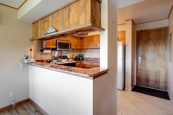 Your fully equipped kitchen features granite countertops, modern appliances, and warm wood cabinetry—everything you need to prepare meals during your mountain getaway.