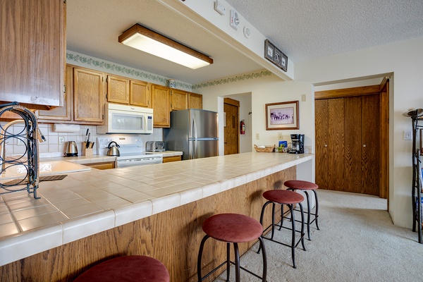 Gather around the welcoming breakfast bar with seating for four, perfect for morning coffee or casual meals. The full kitchen offers everything you need, from stainless appliances to ample counter space for preparing your favorite dishes.