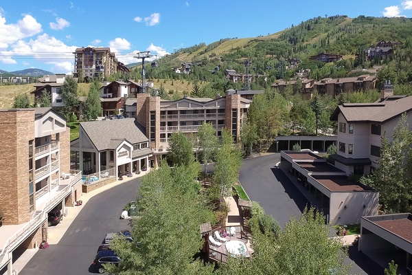 A mountain resort community nestled in a forested valley, with the property building situated among pine trees and ski slopes in a scenic alpine setting.