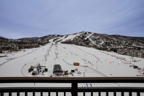 Sweeping ski slopes and mountain views frame this winter getaway, with ski lifts, runs, and a vibrant resort village visible from the balcony.