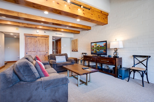 Unwind in your spacious living room with vaulted wood-beam ceilings, comfortable seating, and all the amenities you need for a relaxing stay.