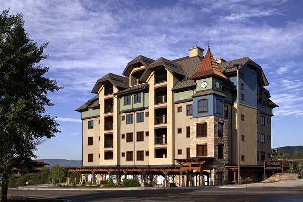 Multi-story vacation rental building featuring distinctive European-inspired architecture with a clock tower, stone accents, and mountain views in the surrounding area.