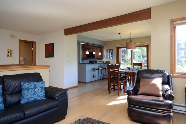Settle into comfortable leather seating as sunlight streams through large windows, where your open-concept living, dining, and kitchen areas invite easy relaxation and memorable gatherings.
